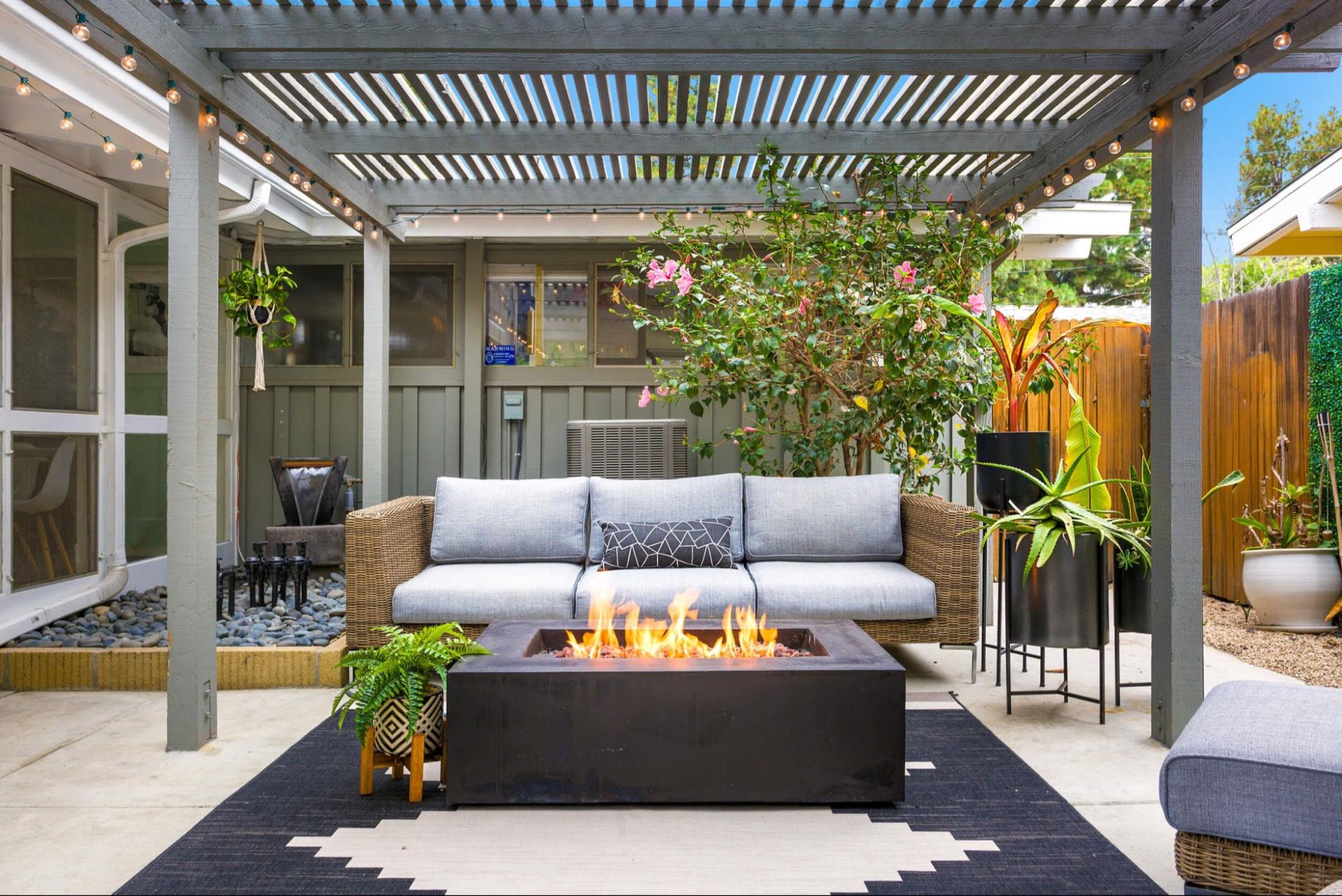 Modern pergola covering an outdoor sofa and fire pit seating area on a backyard patio