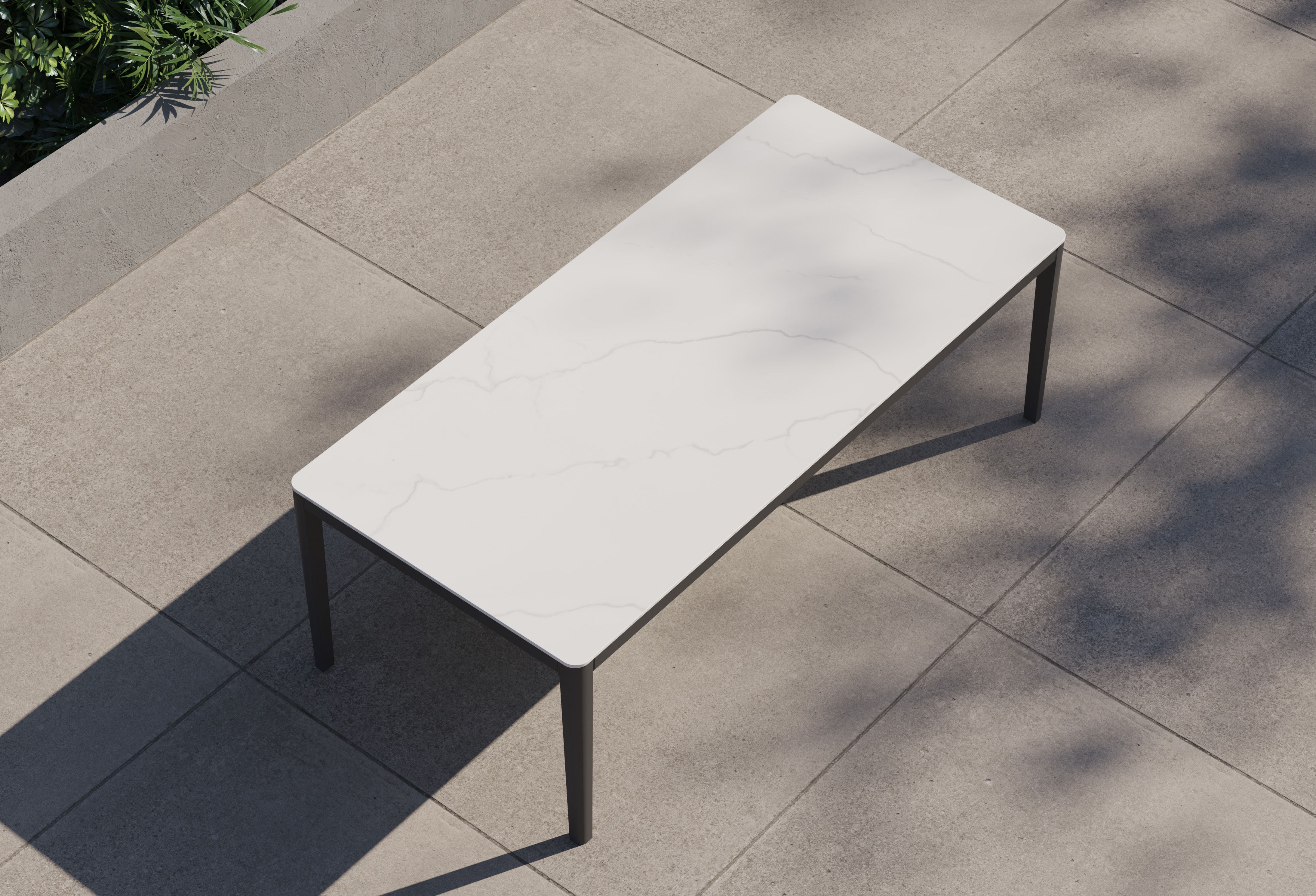 outer-dining table-Charcoal aluminum dining table with gray marble-look sintered stone tabletop shown in a clean studio setting