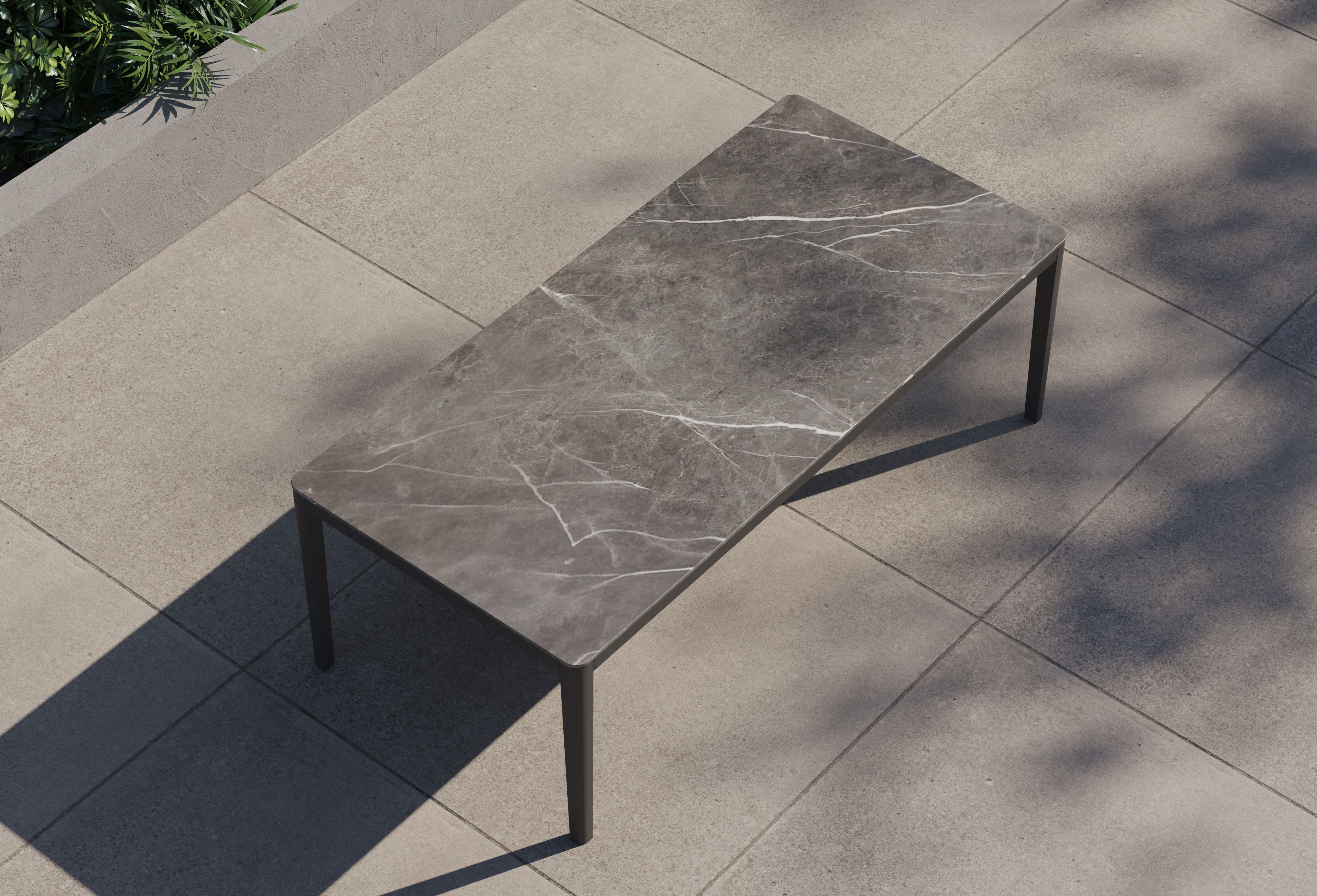 outer-dining table-Charcoal aluminum dining table with gray marble-look sintered stone tabletop shown in a clean studio setting