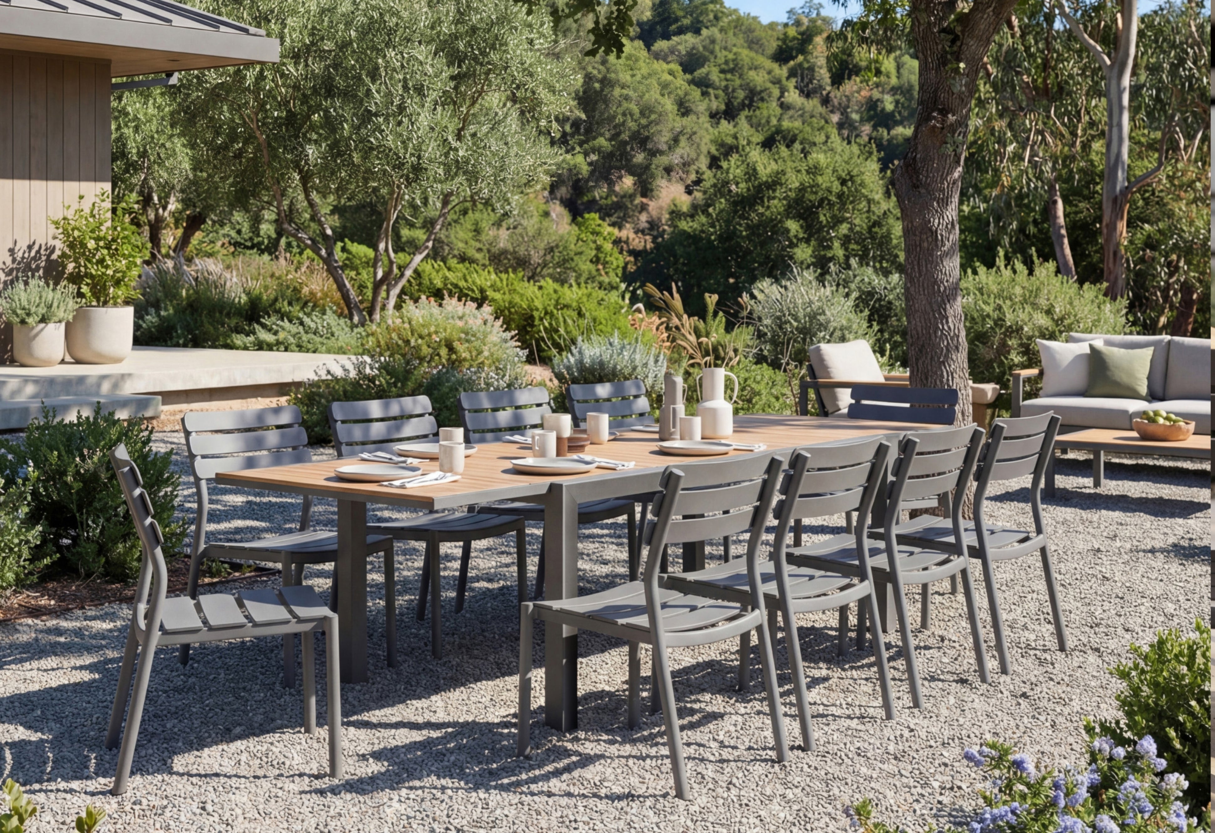 Outdoor dining set with teak table and aluminum chairs in landscaped backyard patio setting with gravel ground and garden greenery