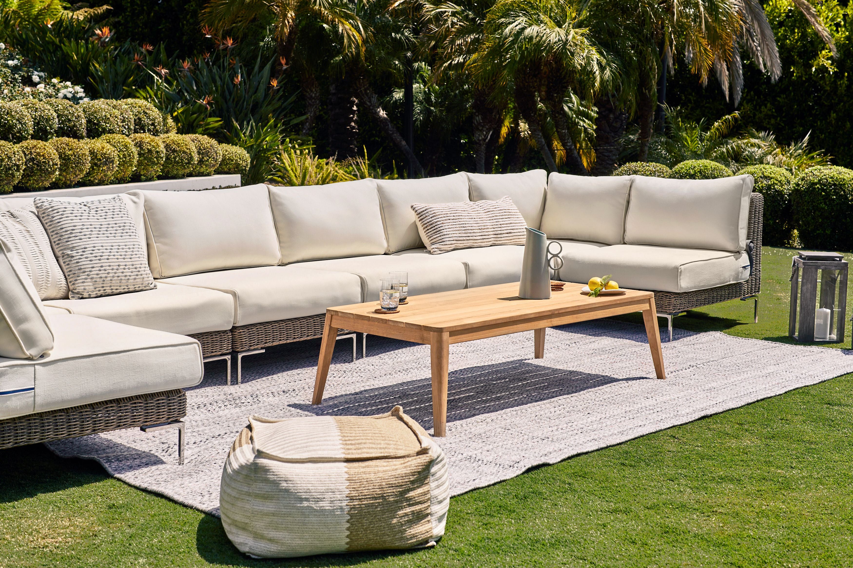 Tapered leg outdoor teak coffee table shown with Outer's durable outdoor rug and wicker sectional. #title_default title