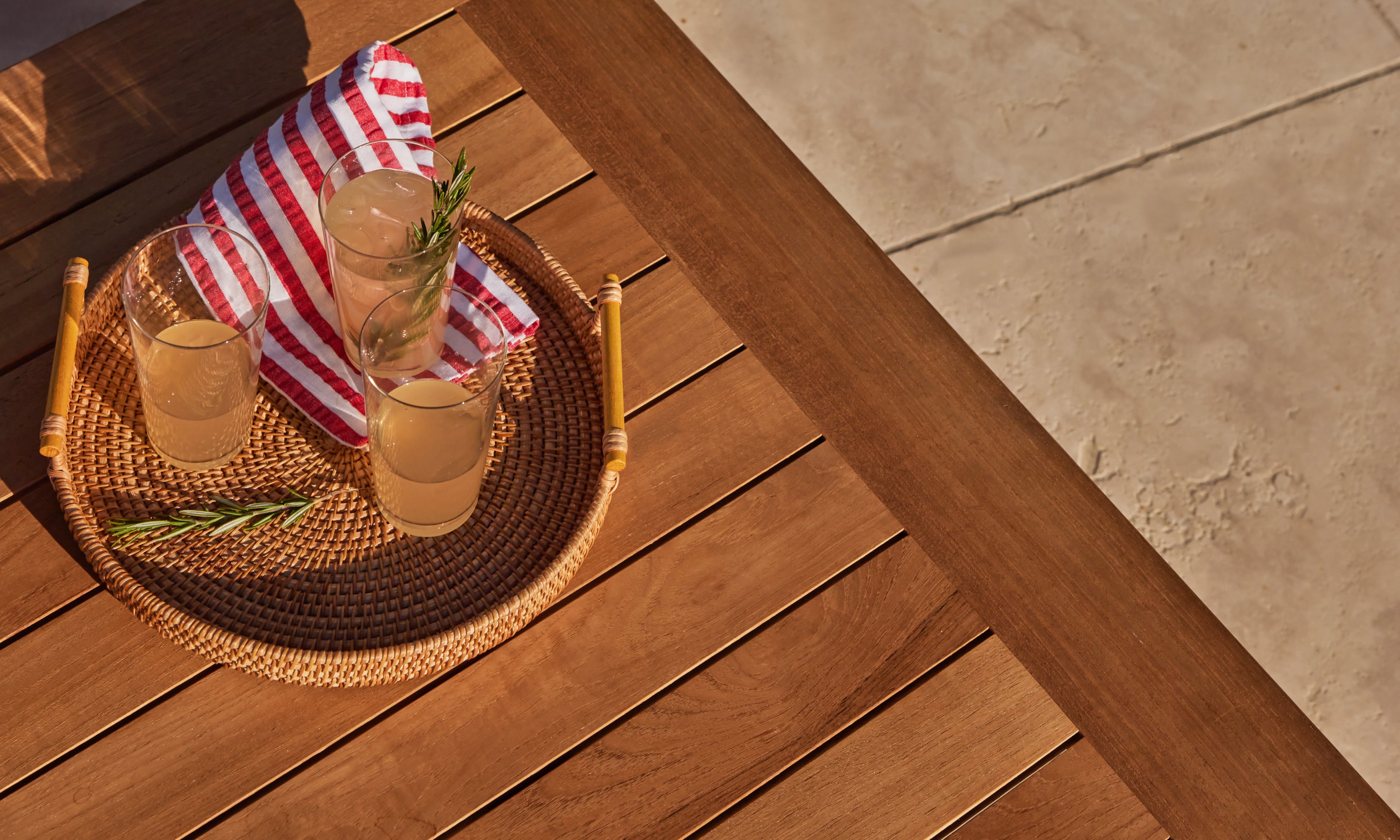 Closeup of Outer teak outdoor coffee table with drinks and serving tray on warm wood slatted surface