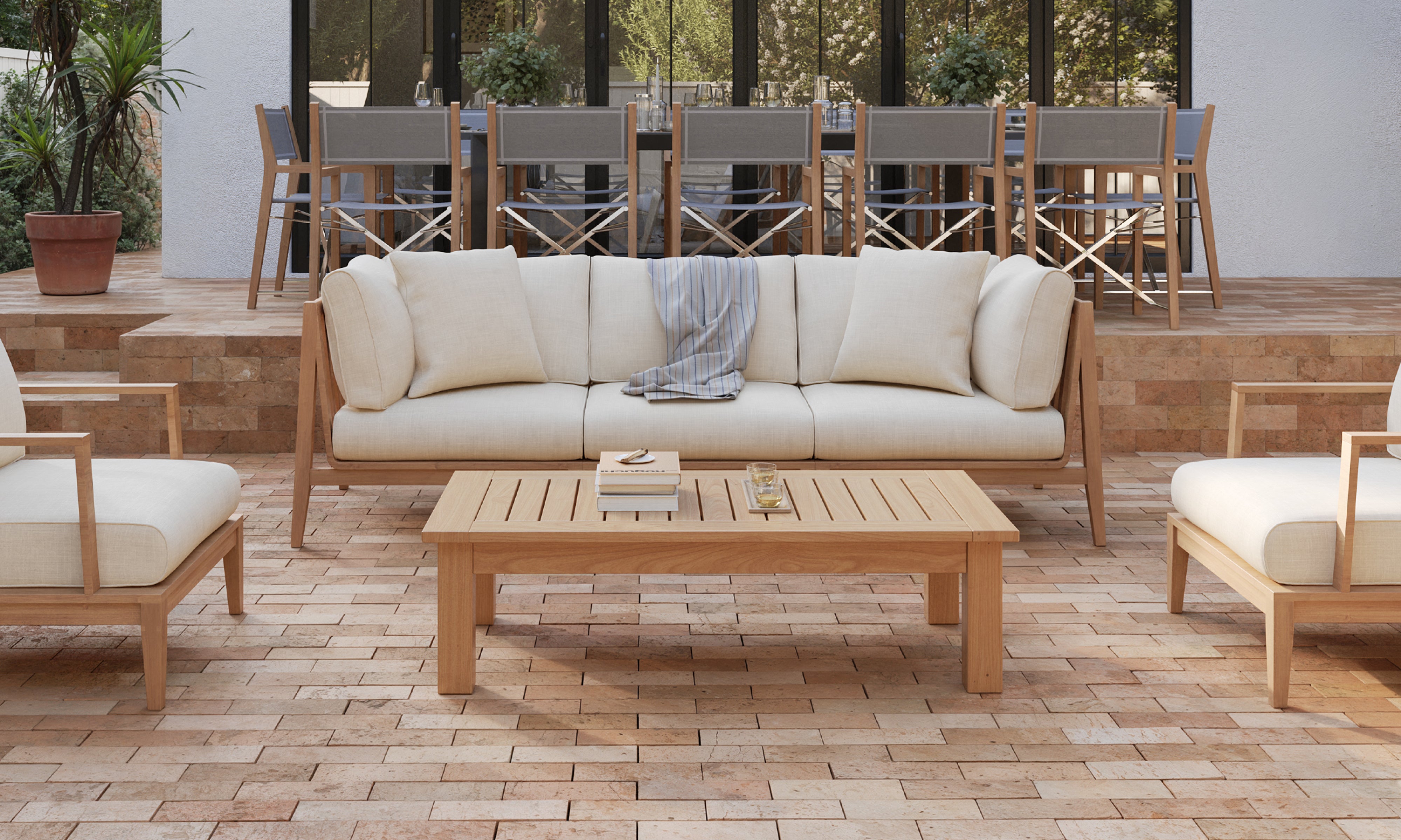 Outer teak outdoor coffee table with matching sofa and lounge chairs on upscale patio entertaining space
