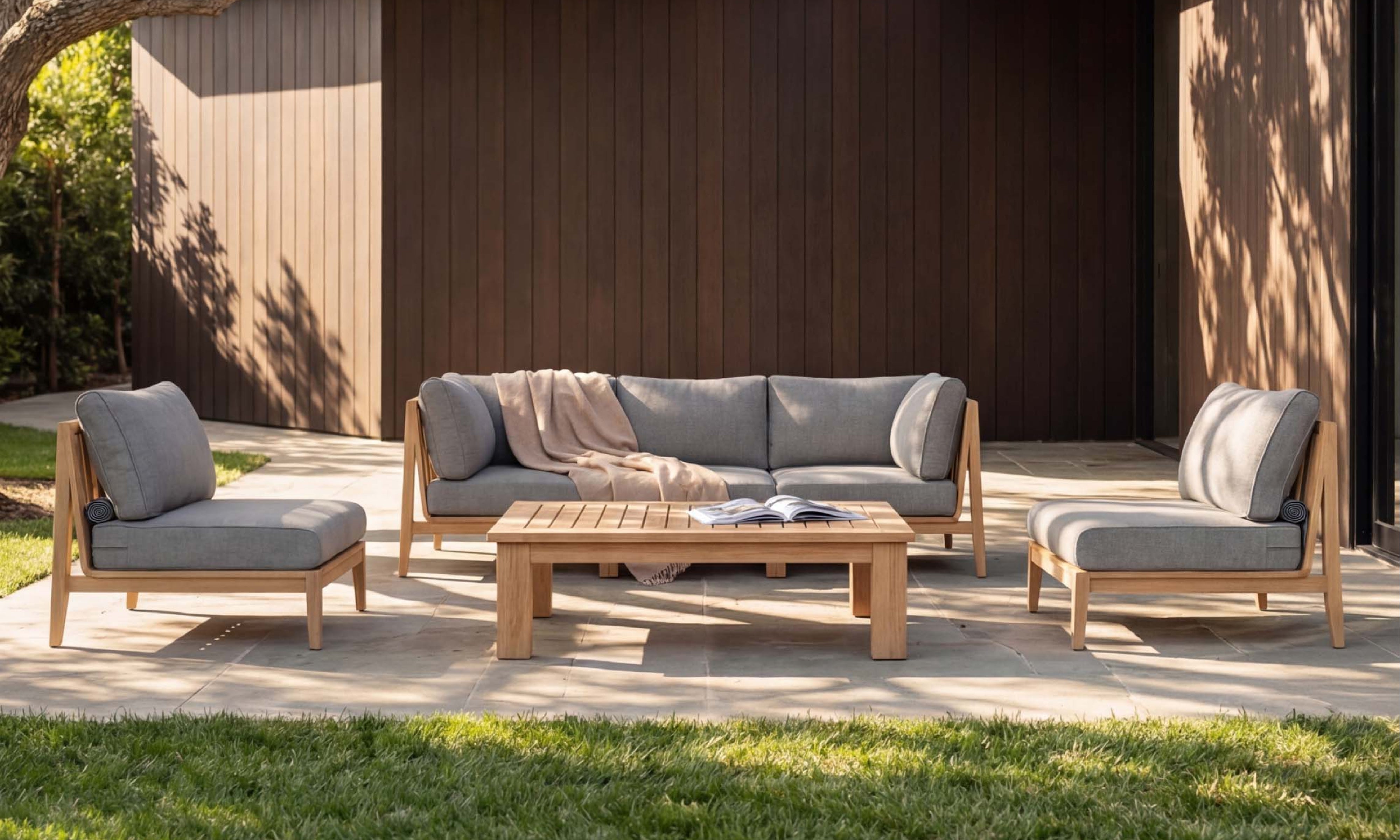 Outer teak outdoor coffee table with sofa and lounge chairs in modern backyard patio arrangement