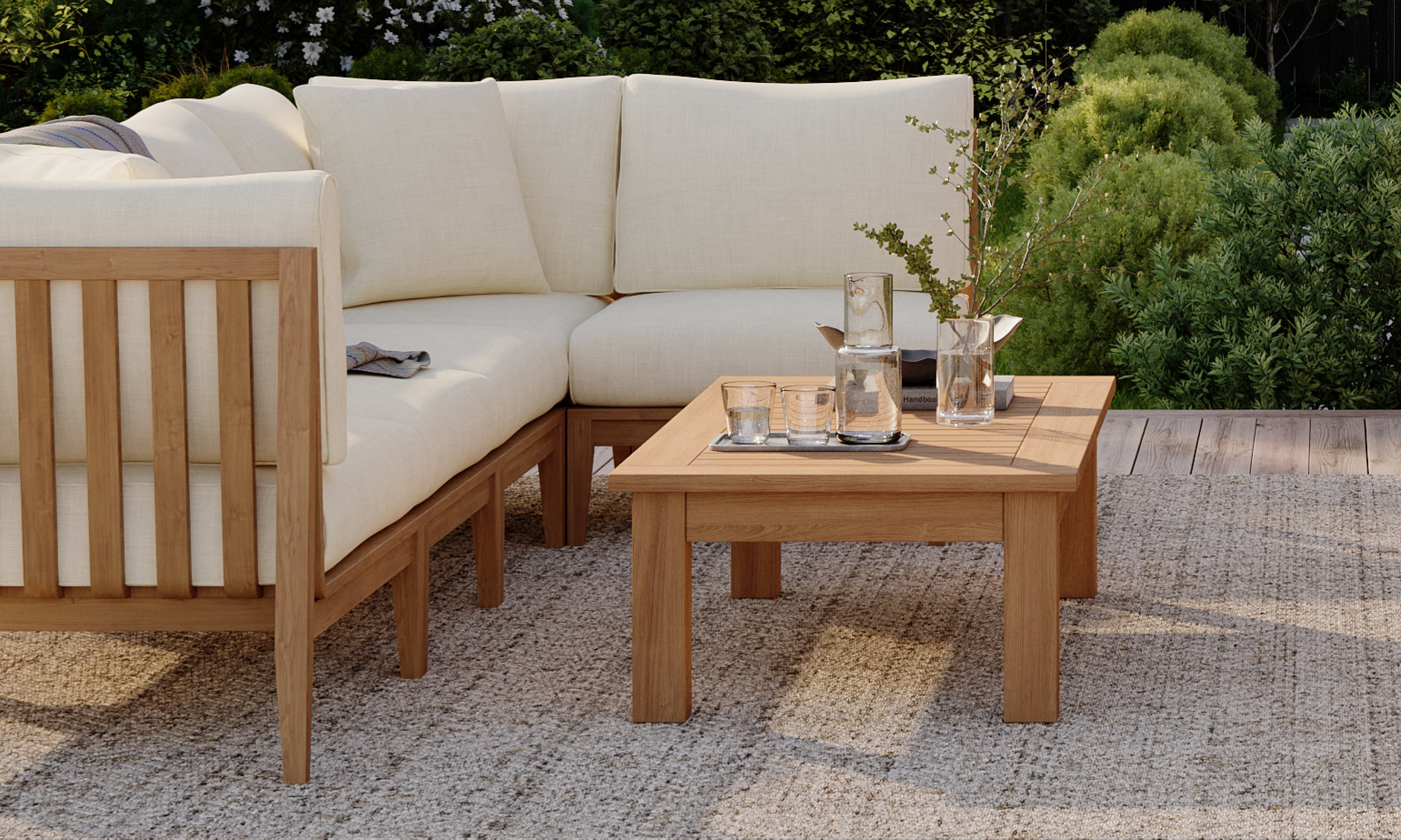 Outer teak outdoor coffee table beside sectional sofa on patio rug in refined garden lounge setting