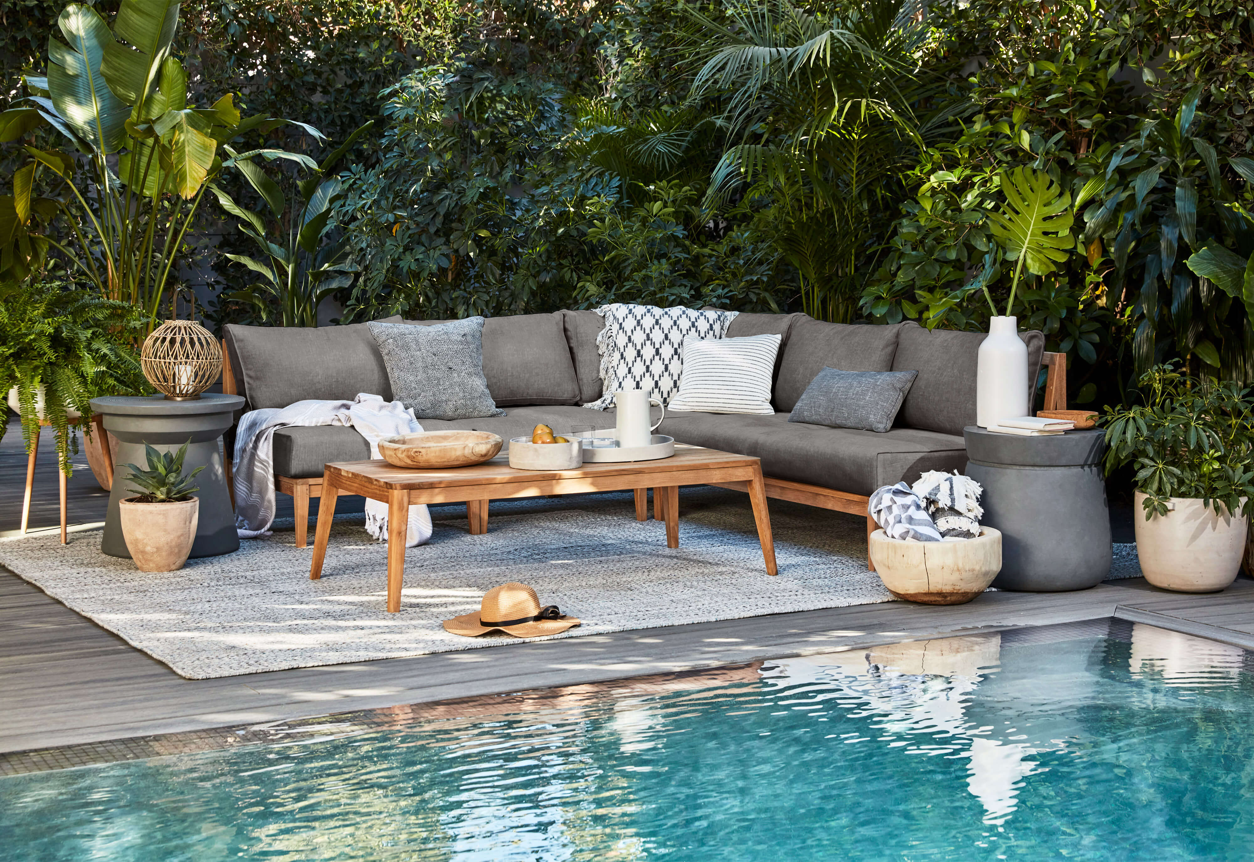 The gray Classic style Concrete Side table shown poolside with a teak sectional sofa. #table color_gray