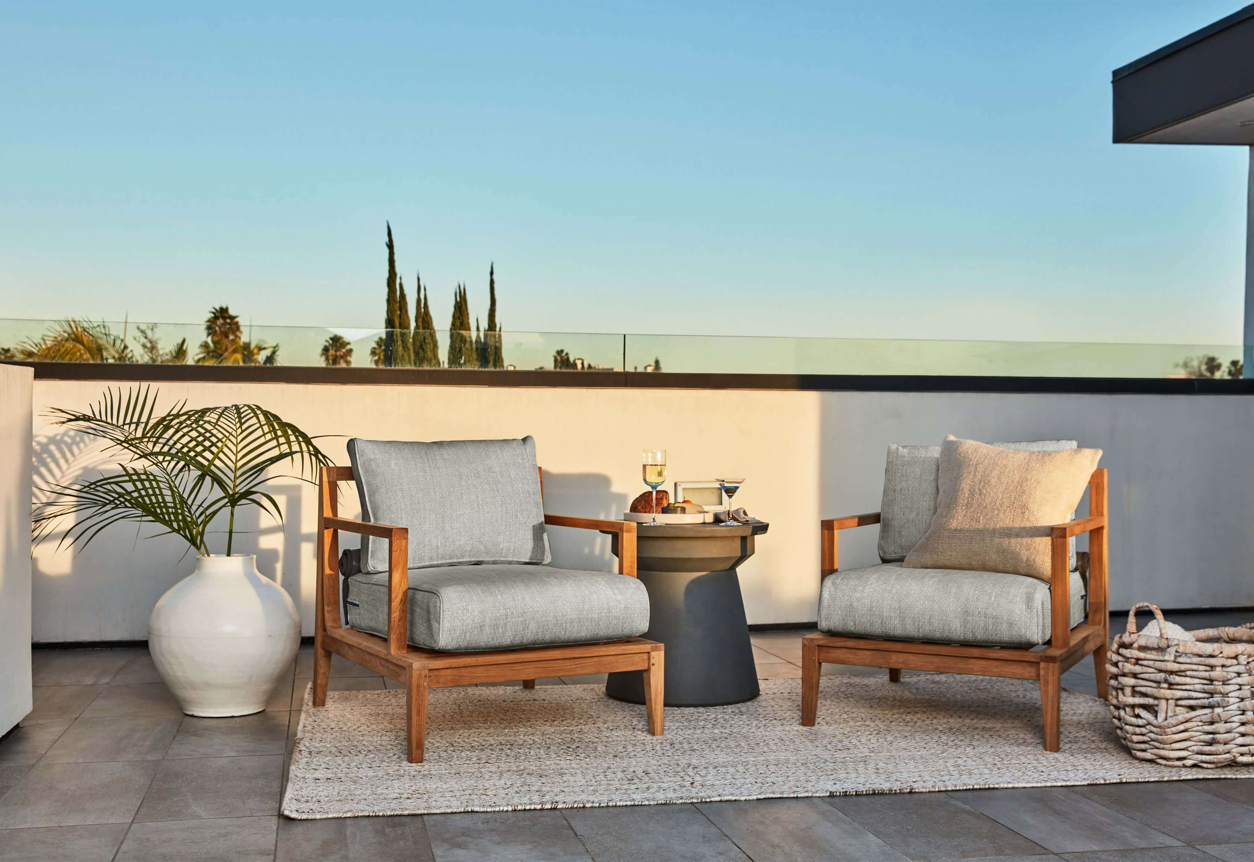 The gray Classic design Concrete Side Table shown on a patio with two teak armchairs. #table color_gray