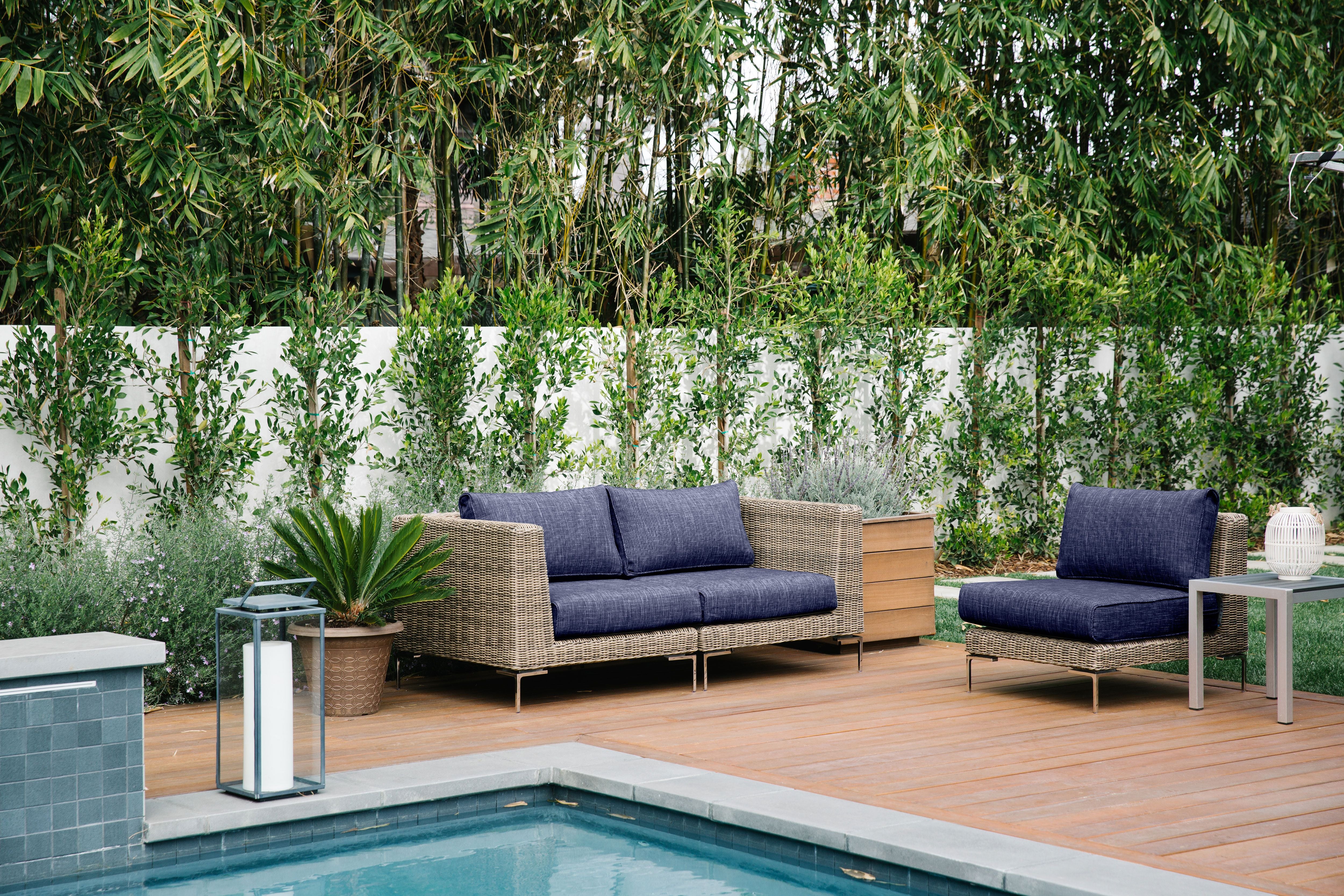 The brown all-weather wicker loveseat and armless chair in navy fabric featured poolside. #color_deep sea navy