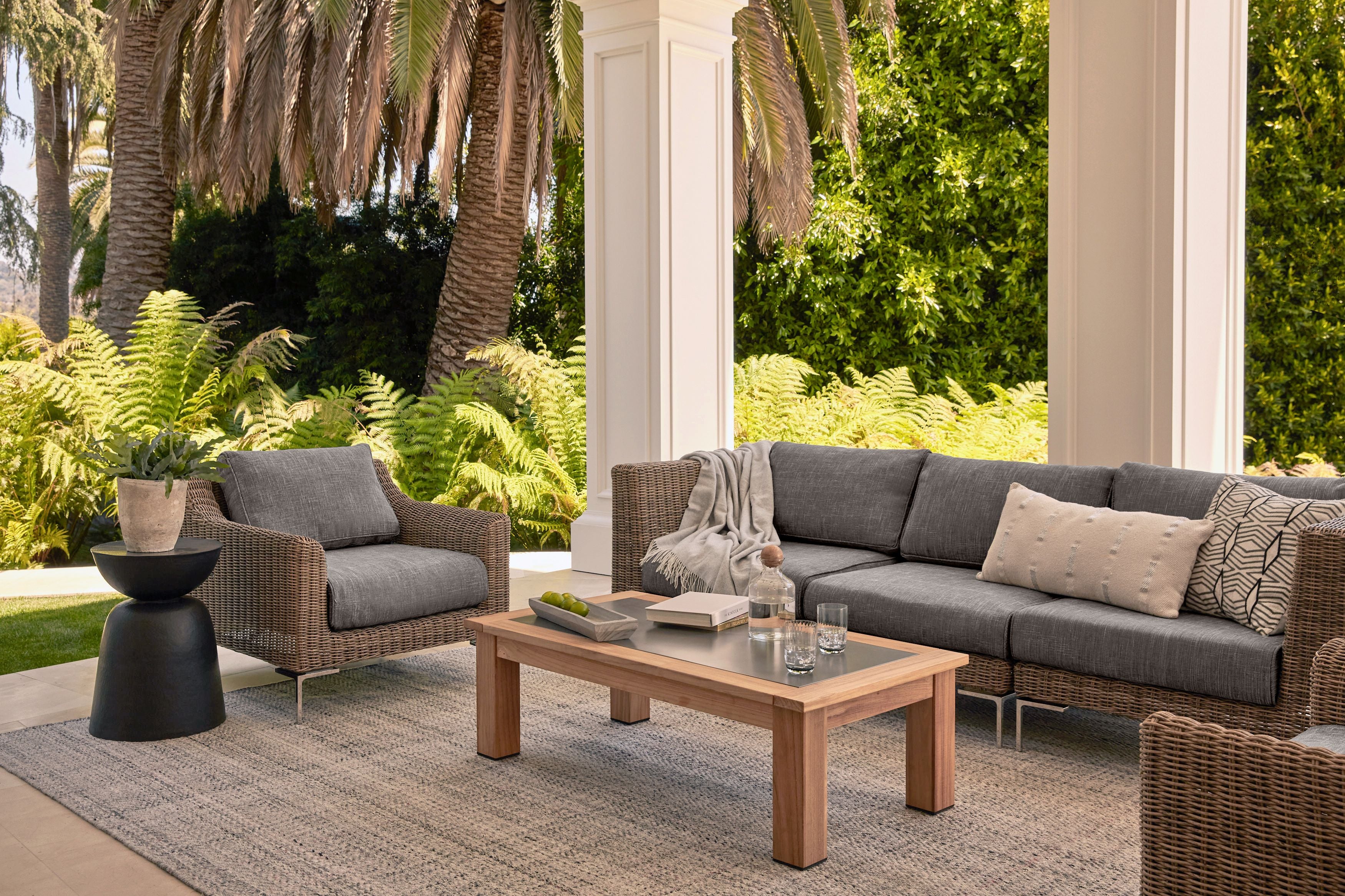 Three seat brown wicker outdoor sofa with armchair featured on a patio with dark pebble gray fabric. #color_dark pebble gray