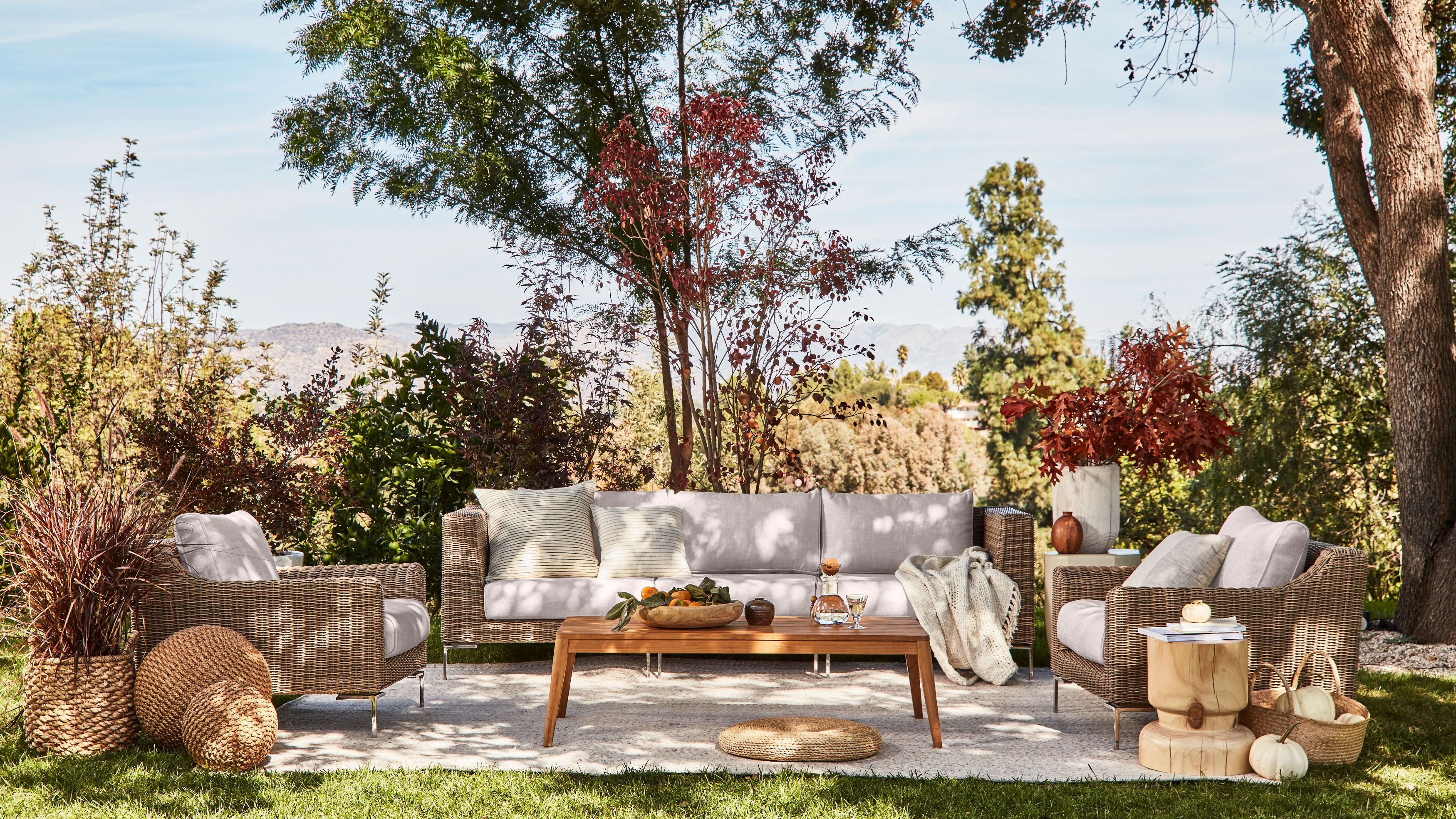 The 3 seat brown wicker sofa with two armchairs in sandstone fabric shown with our outdoor teak tapered leg coffee table.