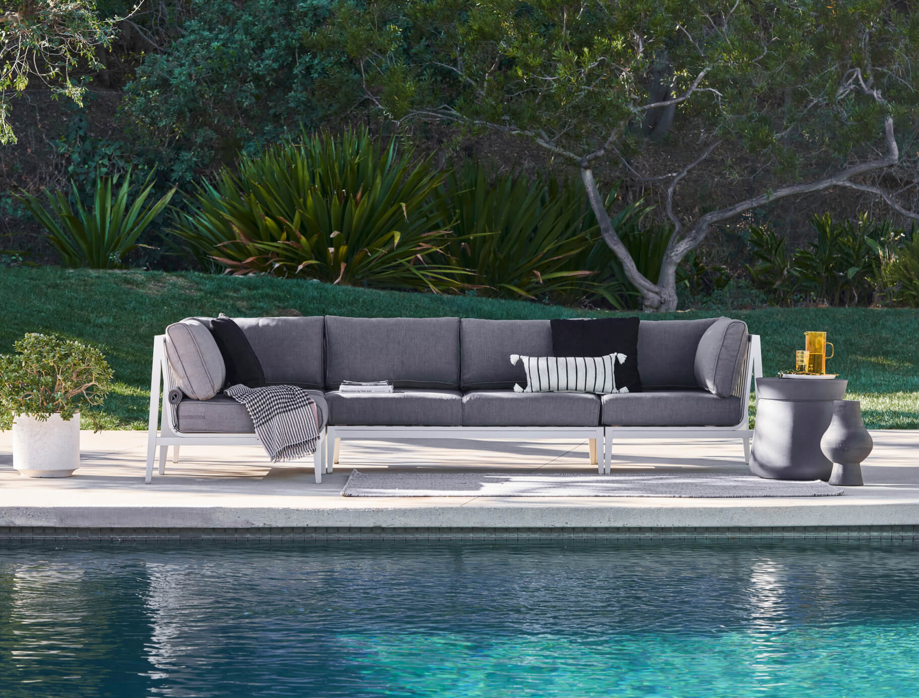 Concrete Outdoor Side Table - Round shown poolside with a white aluminum L sectional.