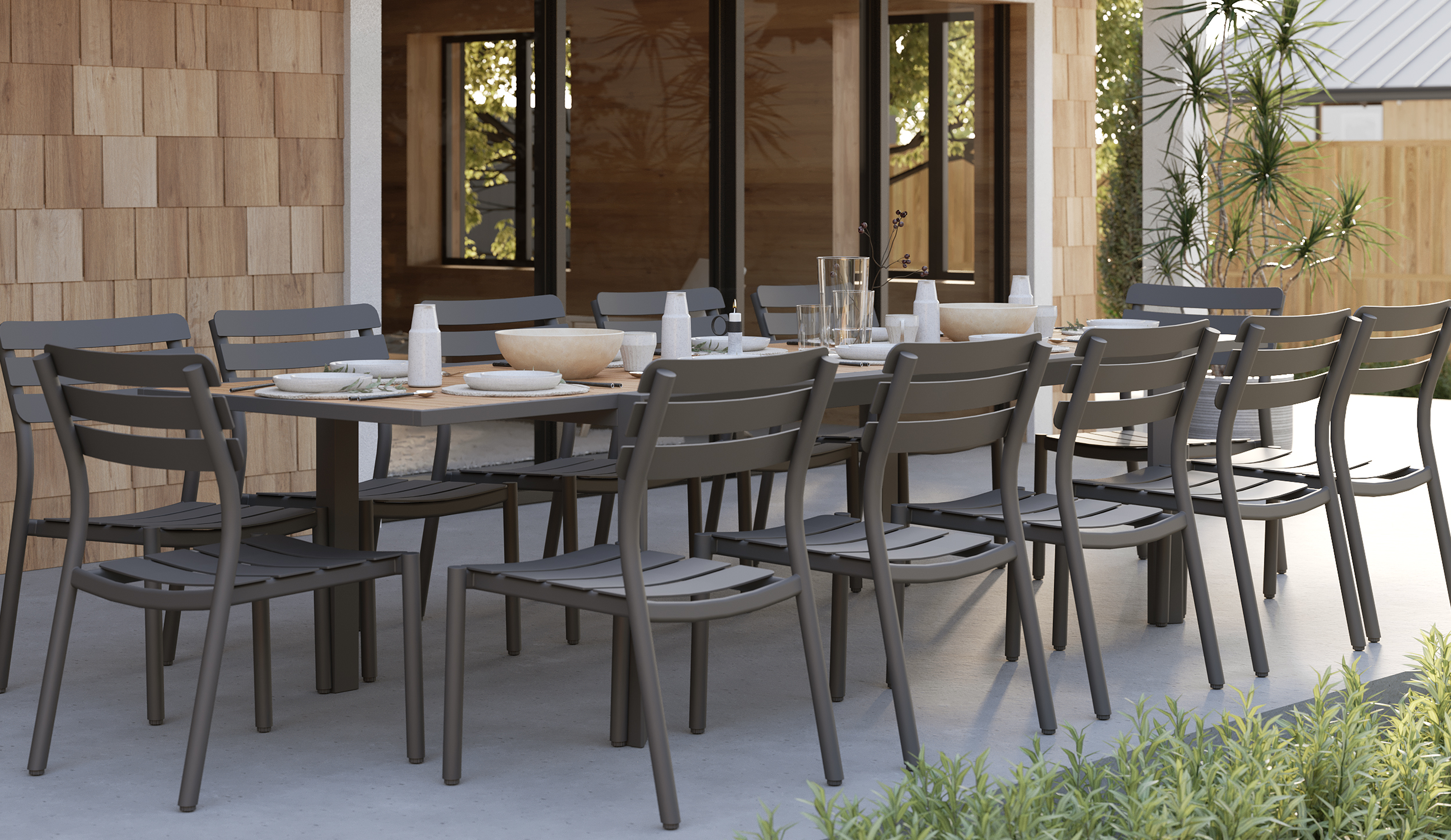 outer-Teak + Aluminum Outdoor Expandable Dining Table + 12 595 Armless Chairs-side view outdoor dining scene with long expandable teak table, charcoal aluminum armless chairs and a fully set table on a modern patio