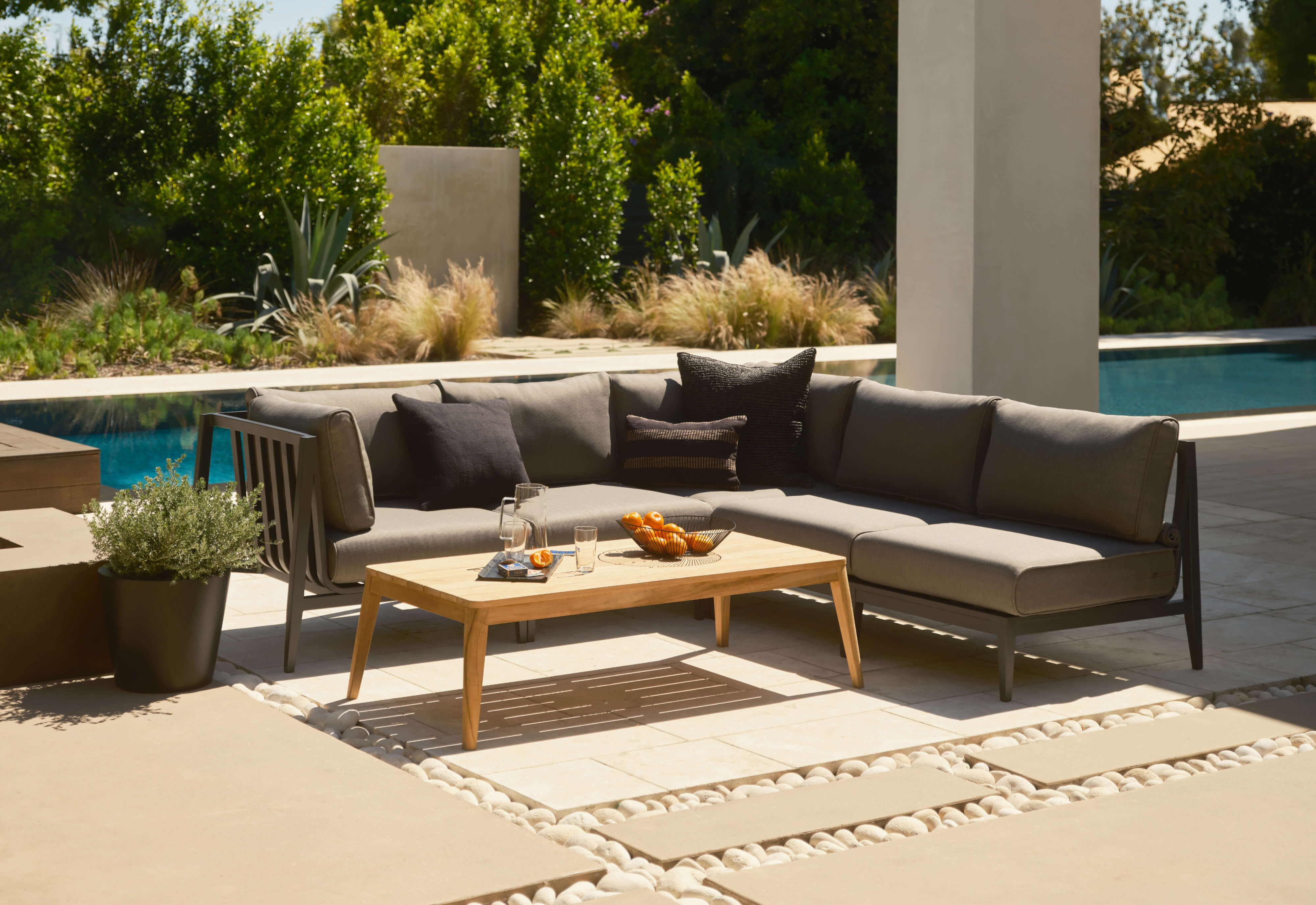 Charcoal aluminum corner sectional with dark pebble gray cushions and the tapered leg teak coffee table.