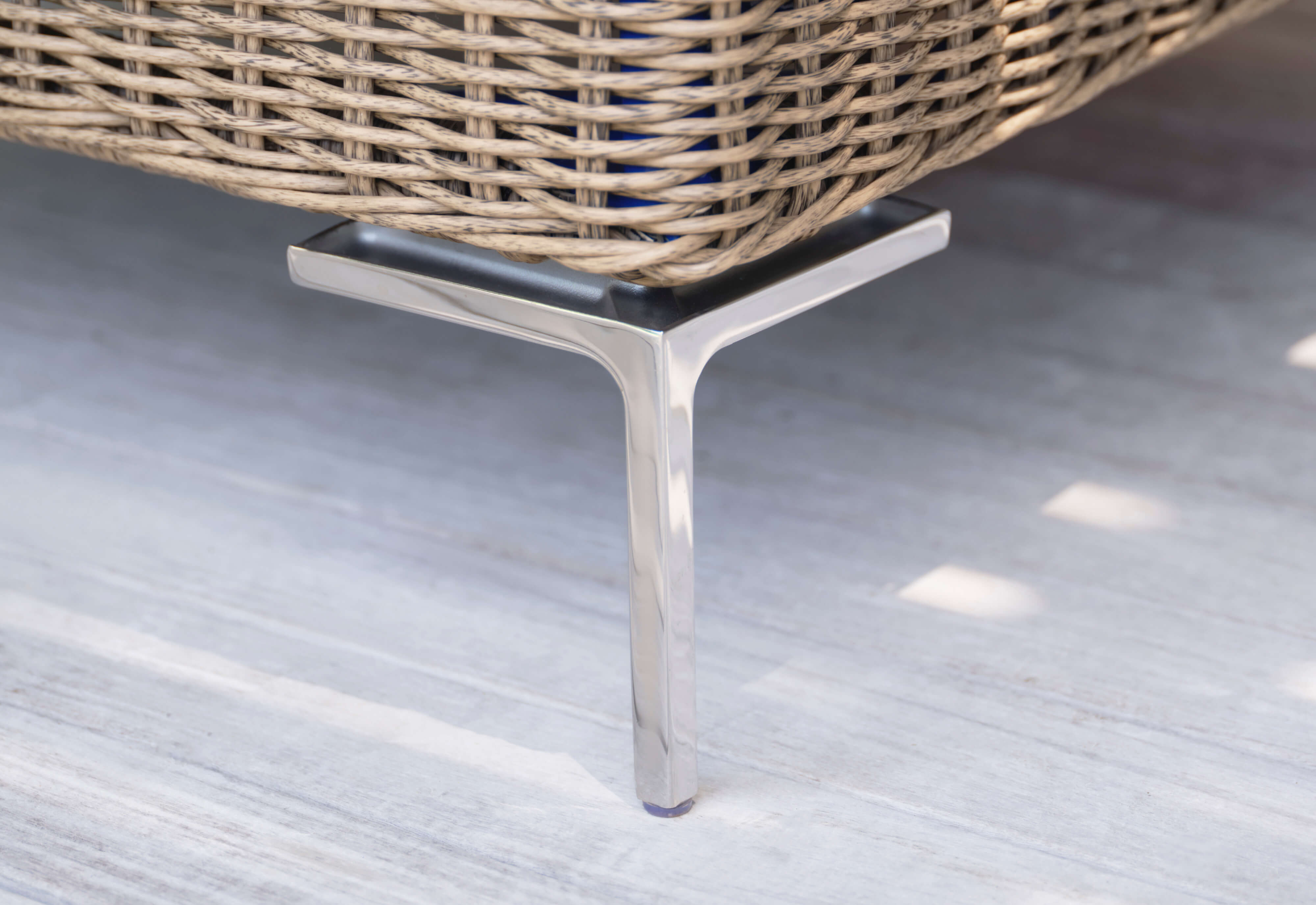 Closeup of one of the polished stainless steel chair legs included with our all-weather wicker seating.
