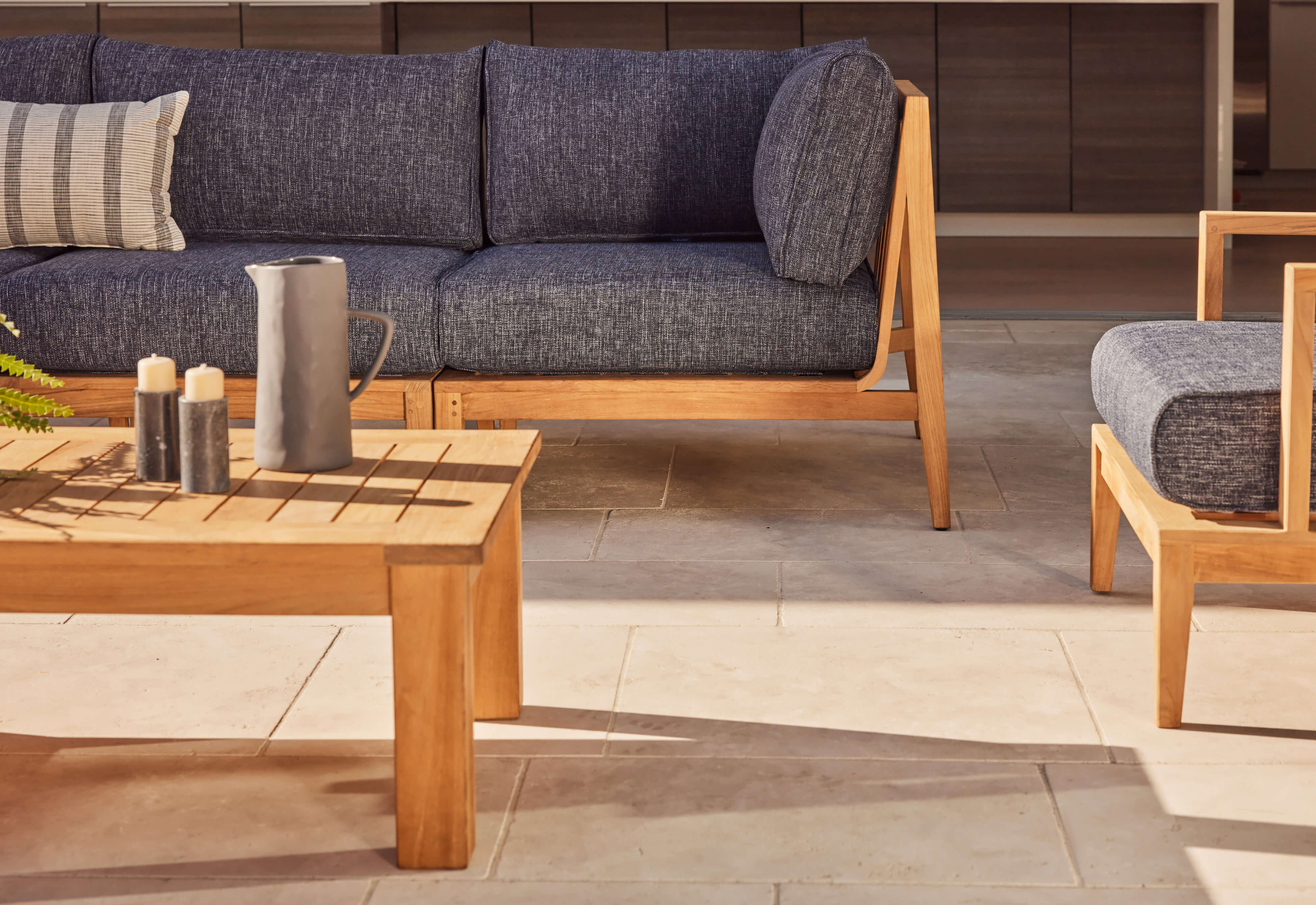 L-shaped sectional 5-piece teak outdoor sofa with navy cushions arranged on a wooden deck.-teak outdoor sofa-outer