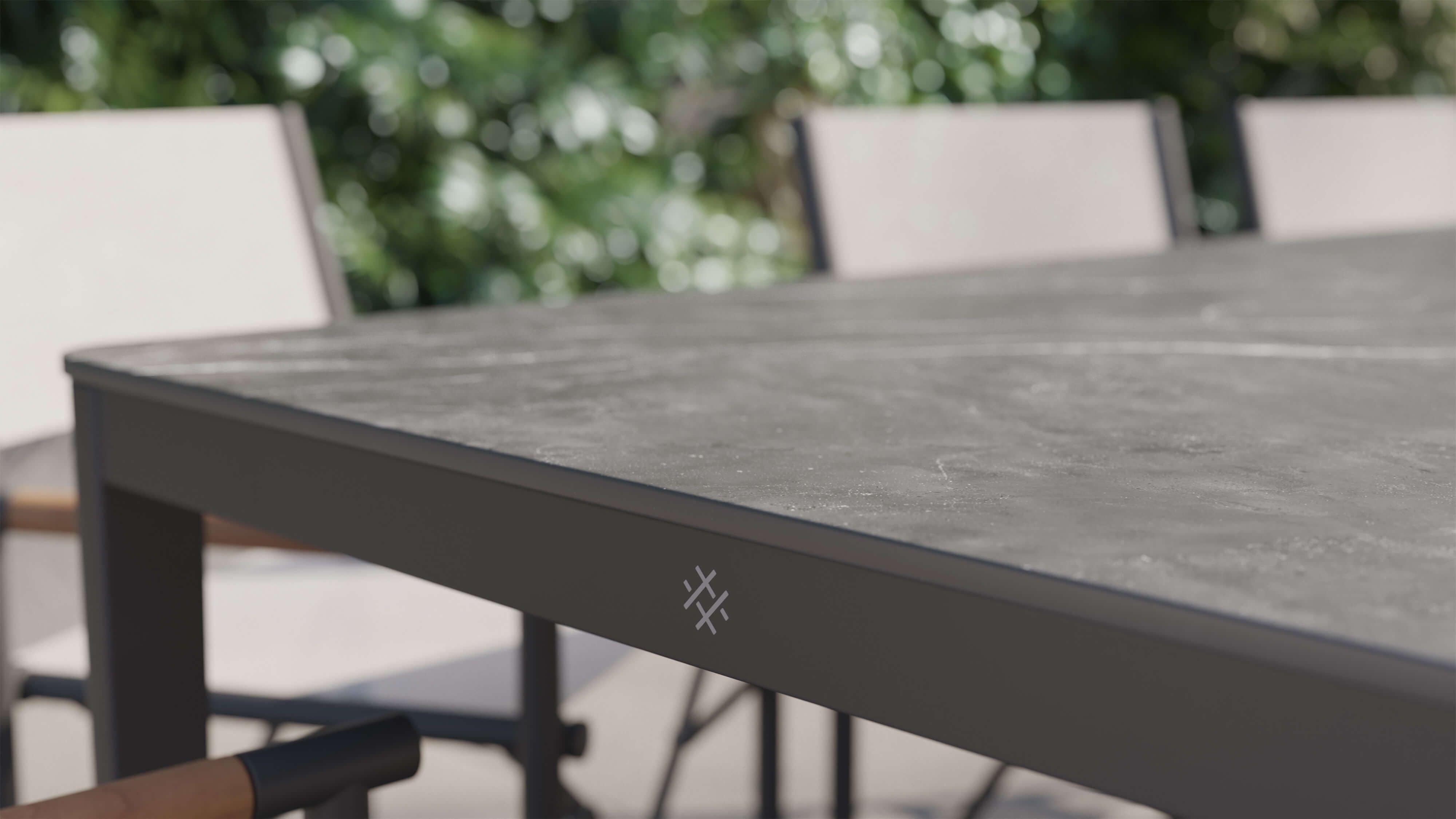 outer-dining table-Close-up of white marble-look sintered stone tabletop with charcoal aluminum frame shown in an outdoor patio setting