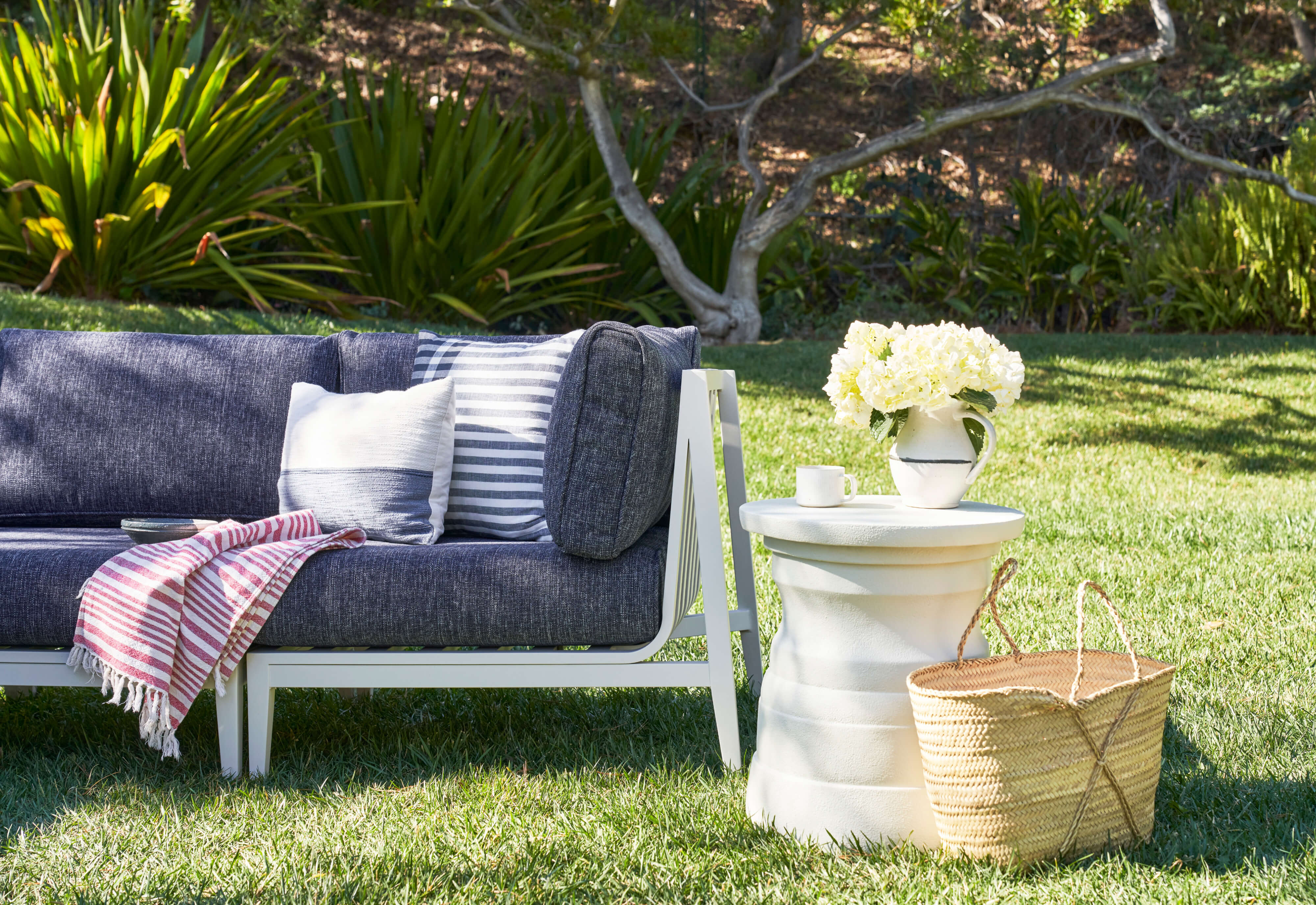 The white Tiered Concrete Outdoor Side Table coordinated with our white aluminum sofa with navy fabric, closeup. #table color_(unavailable) white