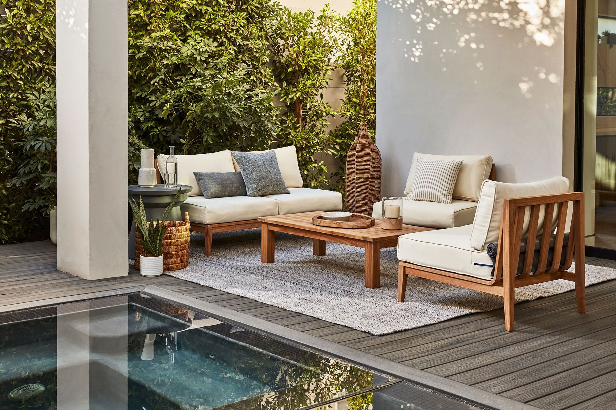 The teak armless loveseat configured with two teak armless chairs in palisades cream fabric with our teak square leg coffee table.