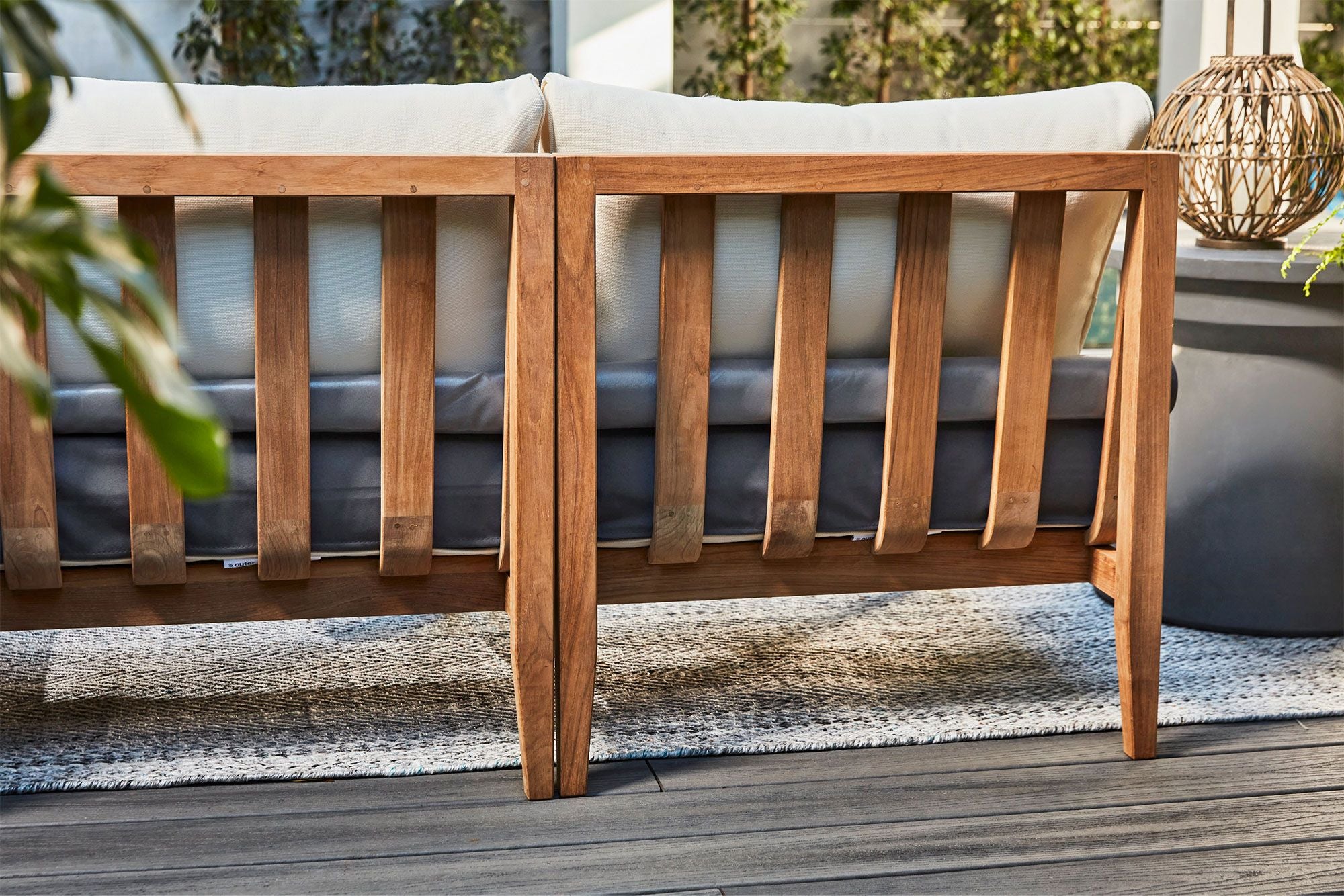 Two modular armless chairs together shown from the back displaying their teak frame and the included OuterShell.