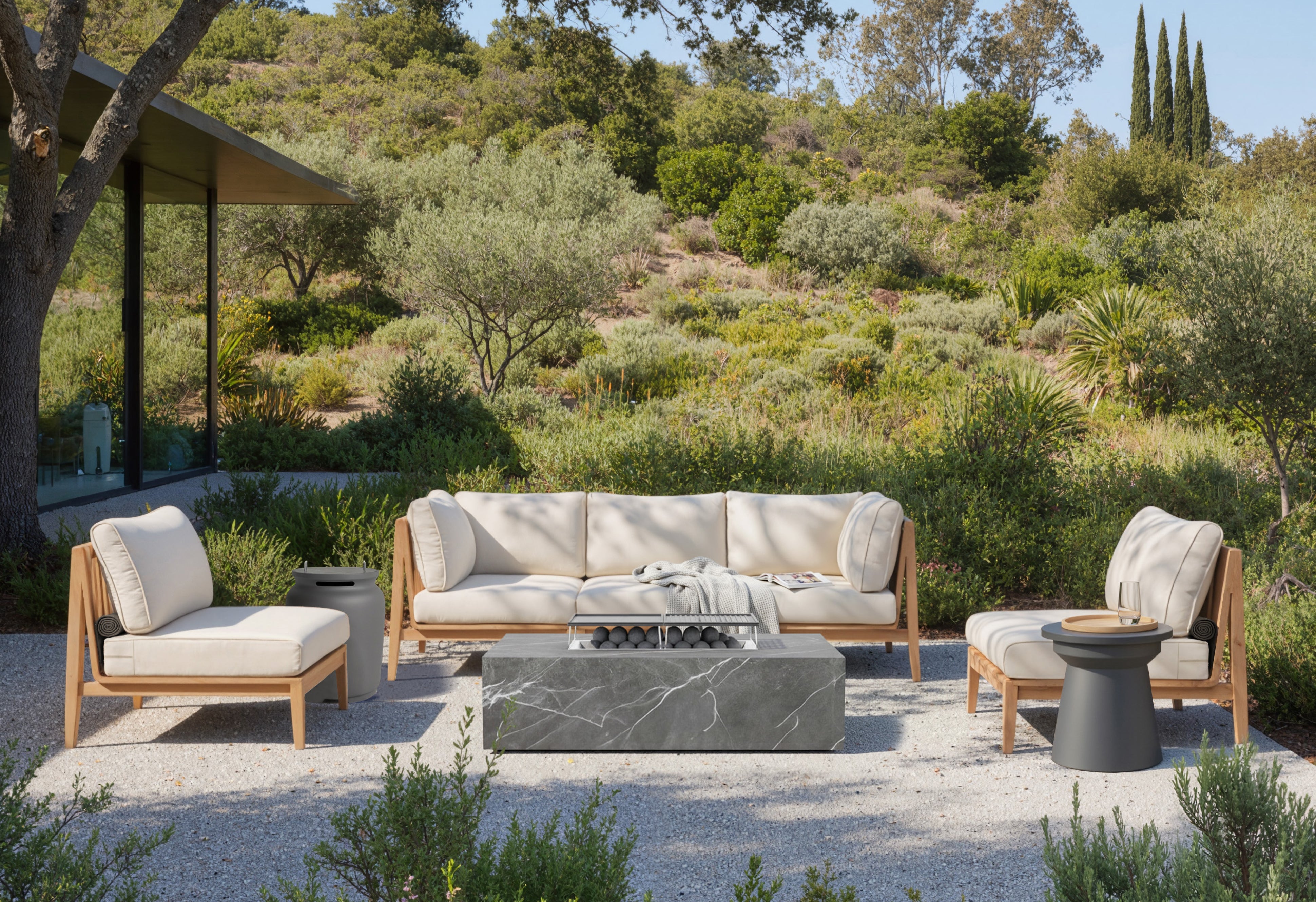 Luxury outdoor teak sofa seating set with lounge chairs and modern fire pit in landscaped backyard patio setting