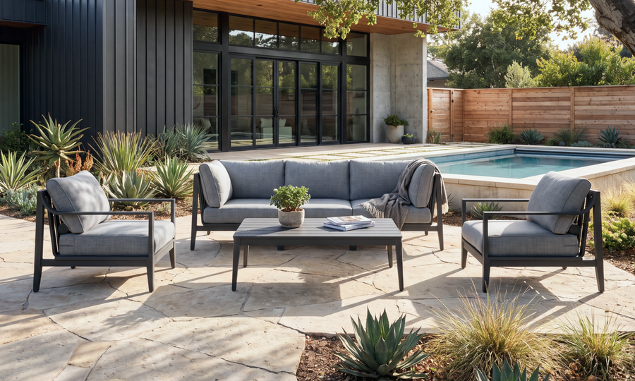 Gray-cushioned charcoal aluminum sofa and two armchairs with a matching coffee table on a poolside patio.