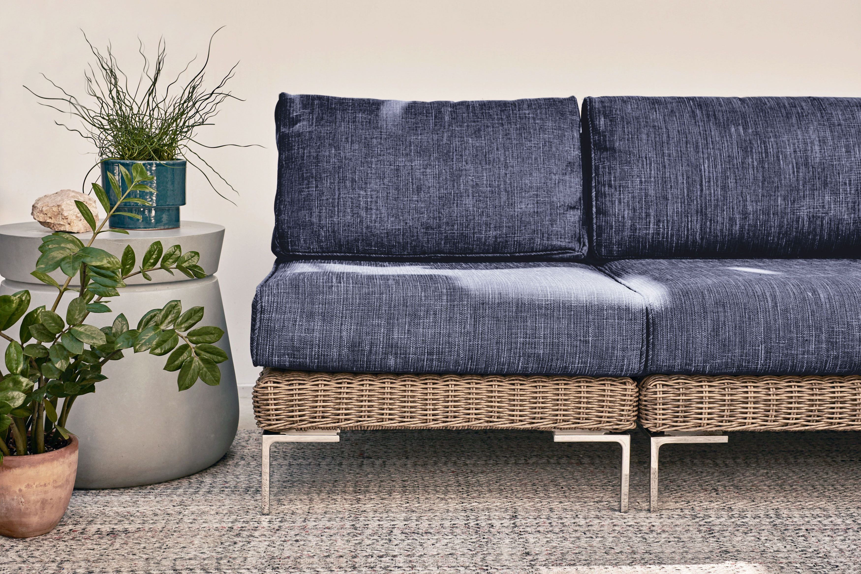 Two modular brown wicker armless chairs in navy joined together to form an armless loveseat shown on top of our sand dune beige outdoor rug. #color_deep sea navy