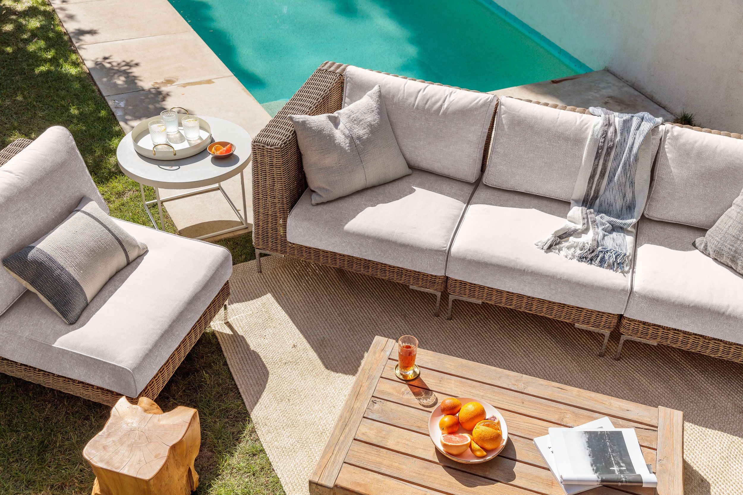 The 3 seat brown wicker sofa in sandstone gray with single armless chair shown poolside on a sunny day. #color_sandstone gray