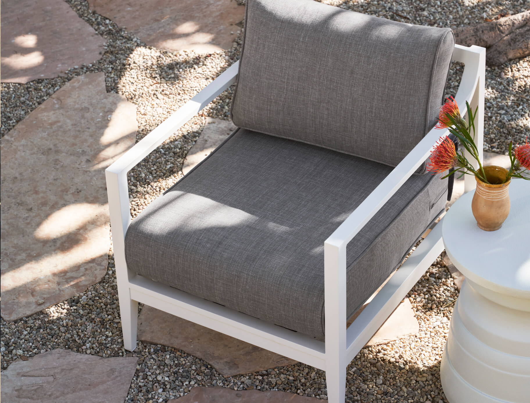 White aluminum armchair in pebble gray fabric shown from the top next to the white tiered side table.
