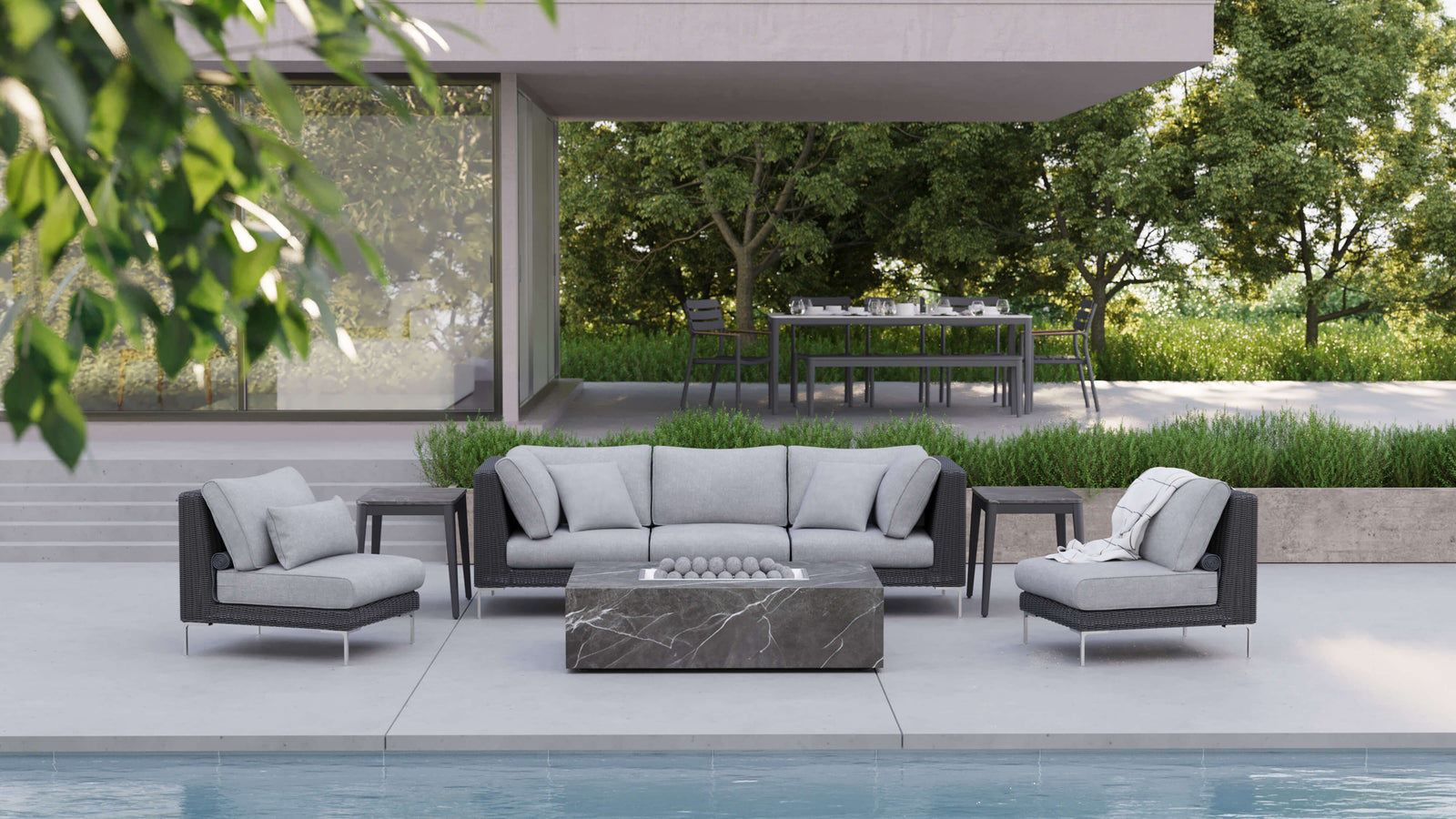 Modern outdoor living room featuring a grey rectangular OuterStone fire pit table and modular patio seating next to a swimming pool.