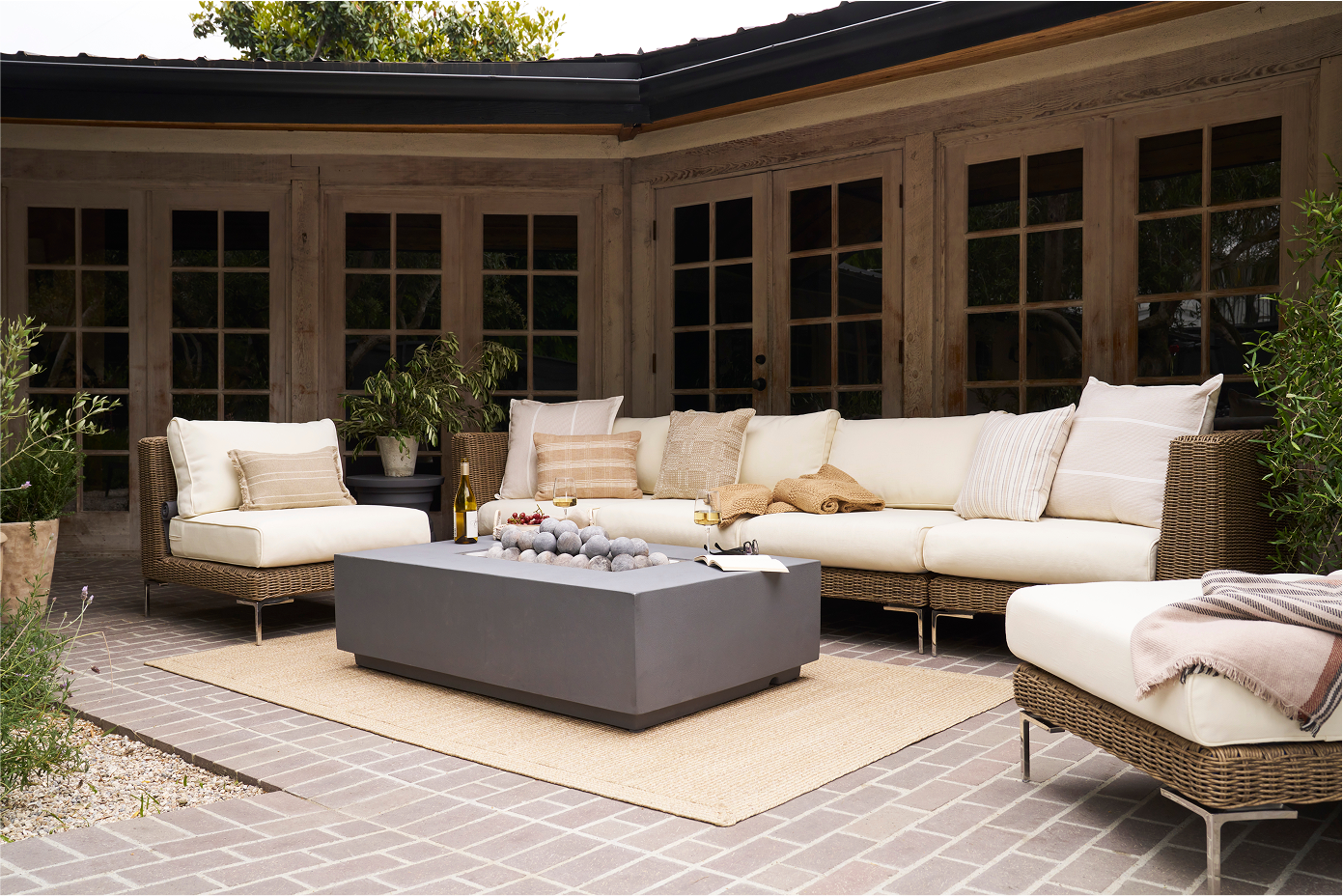Brown wicker outdoor seating and rectangular concrete fire pit on a layered patio