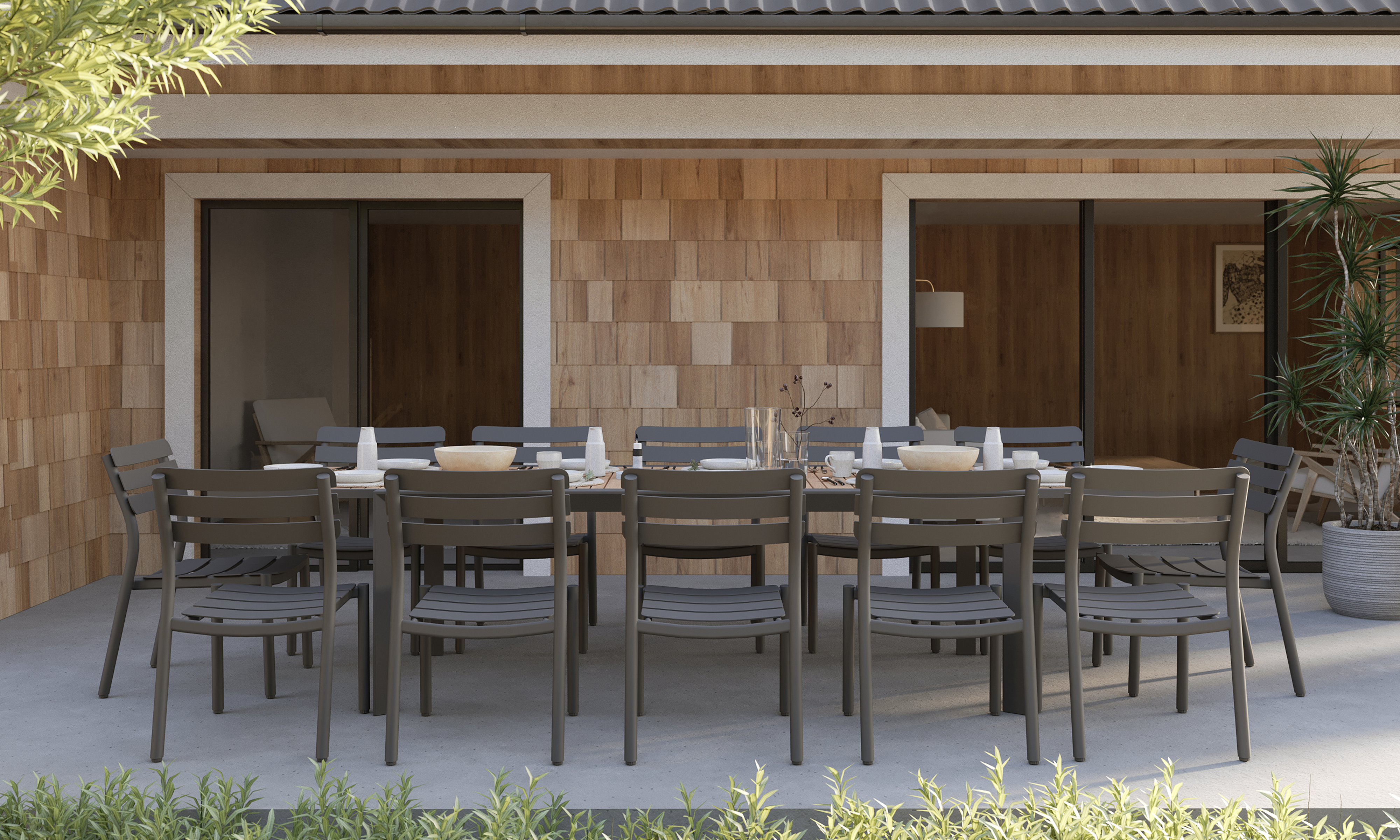  outer-Teak + Aluminum Outdoor Expandable Dining Table + 12 595 Armless Chairs-side view outdoor dining scene with long expandable teak table, charcoal aluminum armless chairs and a fully set table on a modern patio