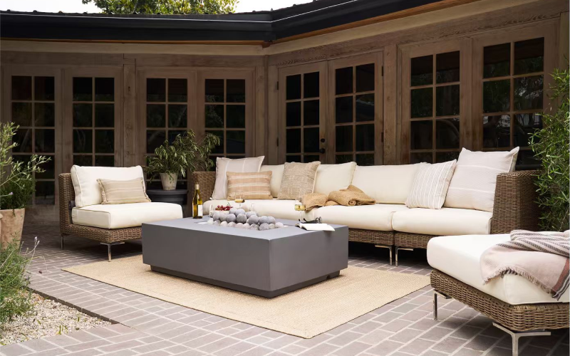 Outer Wicker furniture arranged around a fire pit in a warm backyard setting