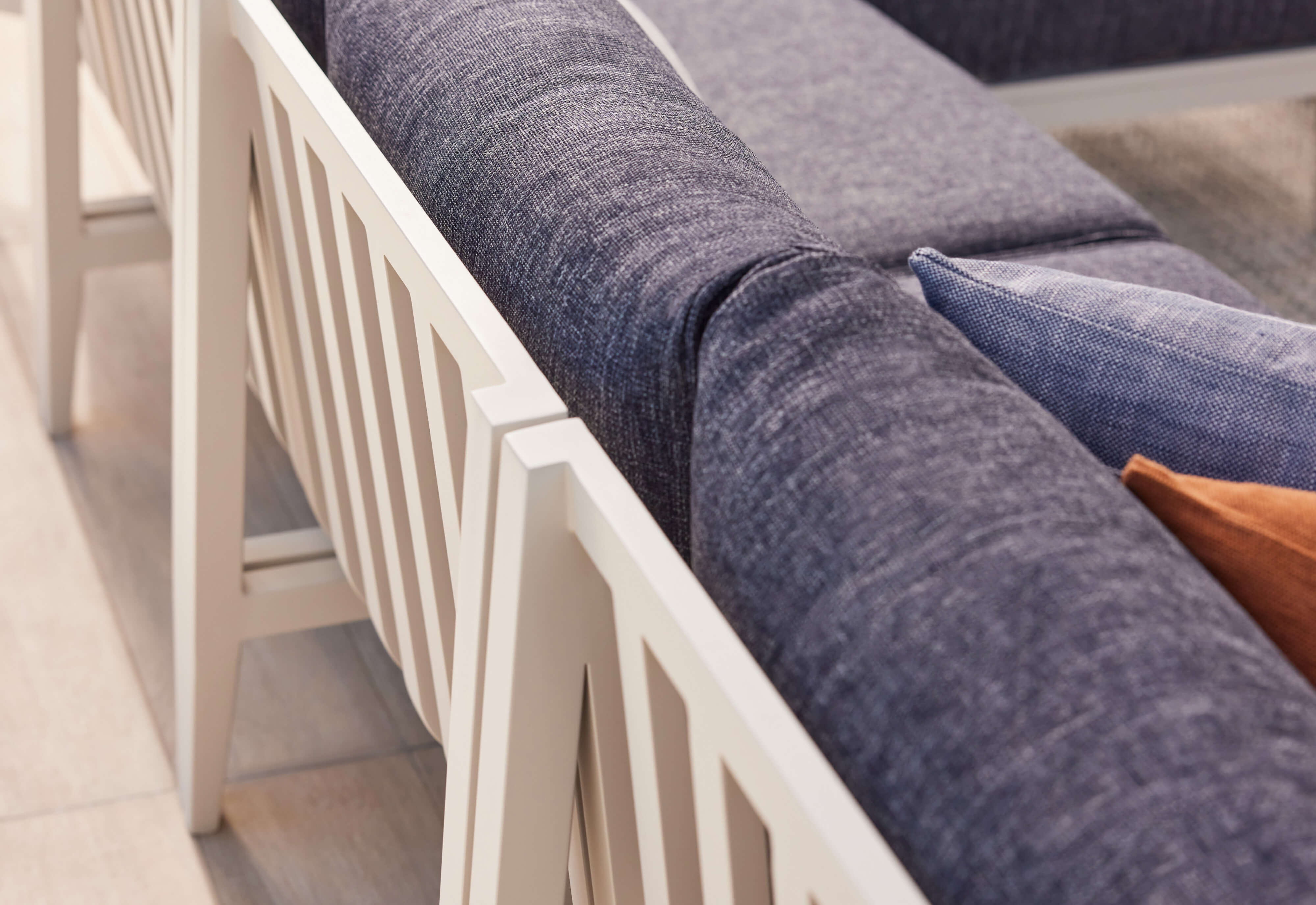 Closeup of a white aluminum sofa with deep sea navy cushions from the top/back angle.