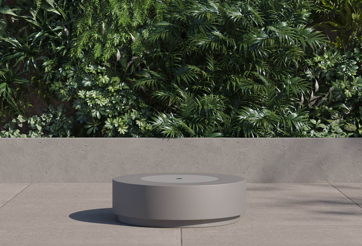 Round concrete fire pit table with burner lid cover closed functioning as an outdoor coffee table.